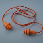 Yellow hearing safety protection earplug isolated on a grey background.